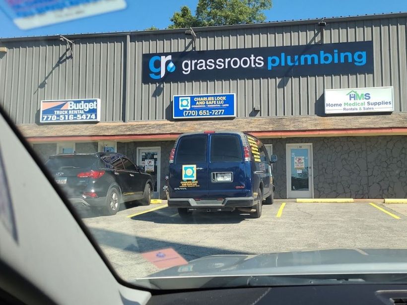 A blue van is parked in front of a building that says grassroots plumbing