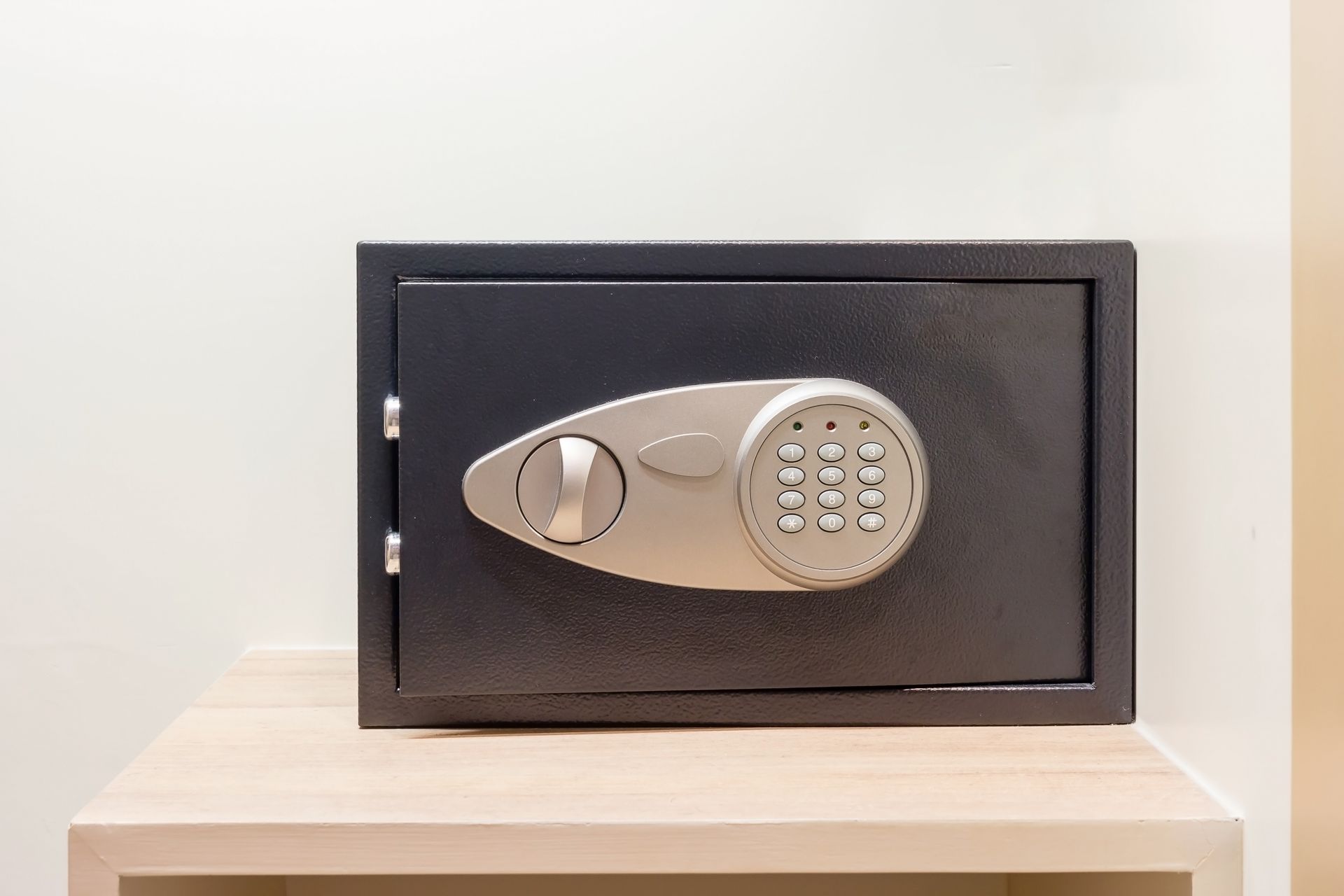 A digital safe is sitting on top of a wooden shelf.