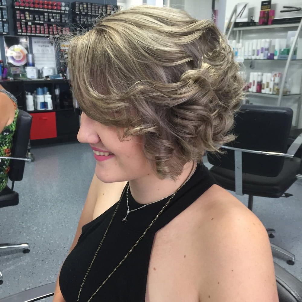 A Woman in a Black Top is Sitting in a Hair Salon — Rayzr Hair Artistry in Eli Waters, QLD