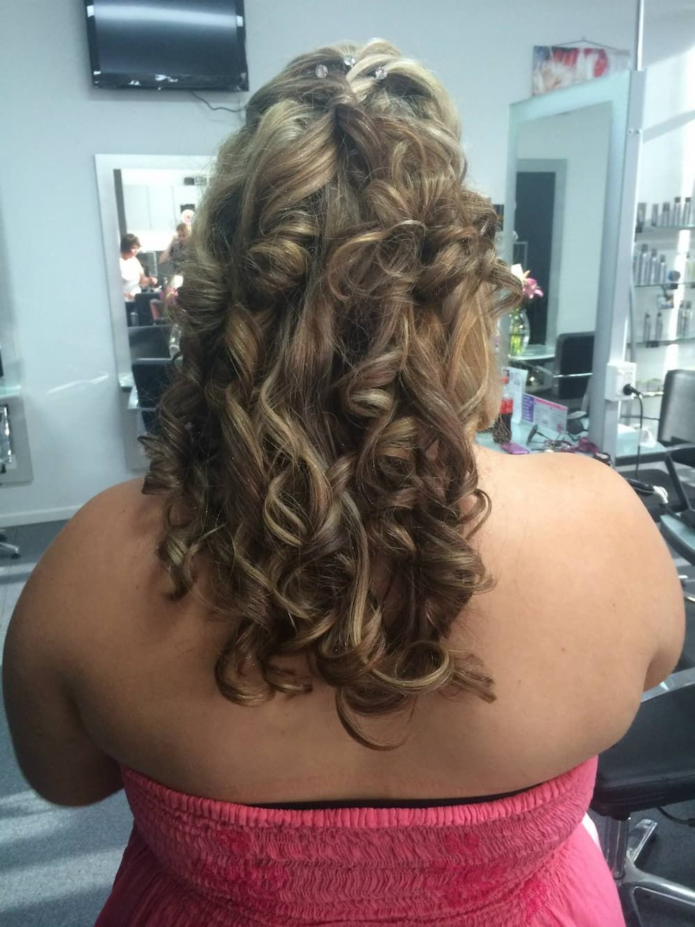 A Woman in a Pink Dress is Getting Her Hair Done in a Salon — Rayzr Hair Artistry in Eli Waters, QLD