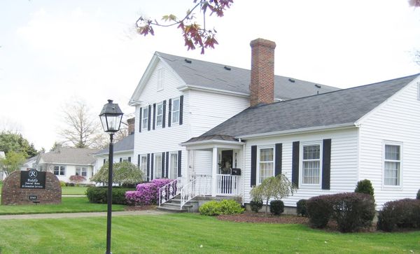 A white house with black shutters and a chimney