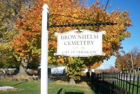 A sign for brow helm cemetery is hanging from a pole in front of a cemetery.