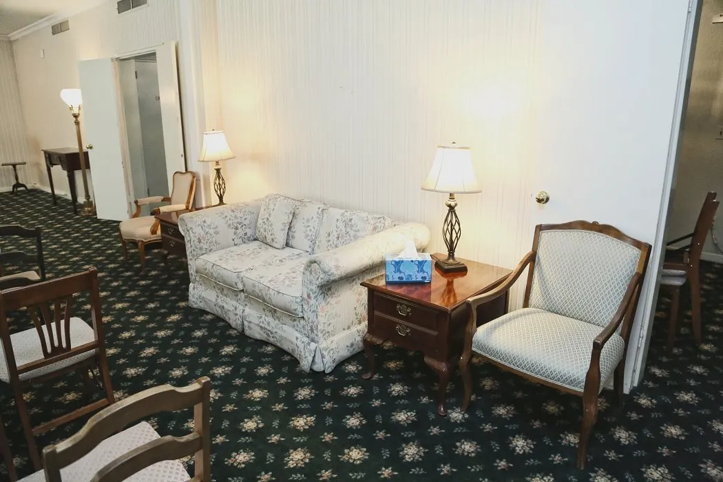 funeral home facilities room with white sofa and two white chairs