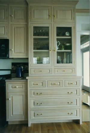 A kitchen with a dresser , cabinets , drawers and a stove.