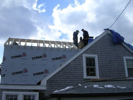 A group of men are working on the roof of a house