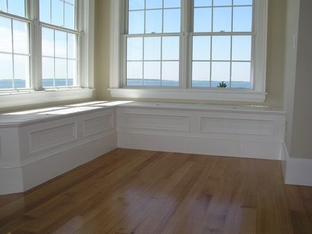 An empty room with a window seat and hardwood floors