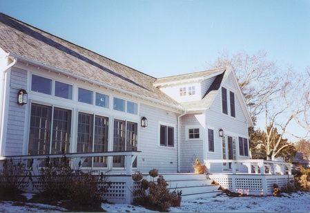 A large white house with a porch in the snow