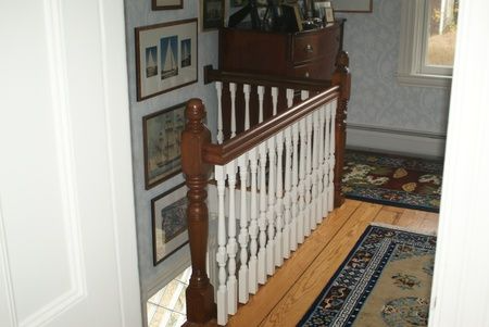 A wooden staircase with a white railing and a rug on the floor