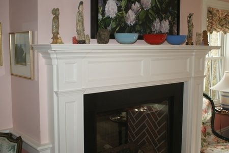 A living room with a fireplace and a painting on the mantle