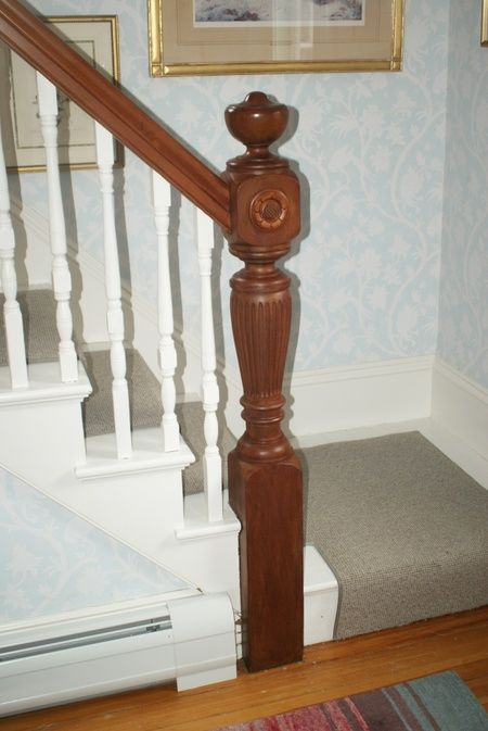A staircase with a wooden post and white railing