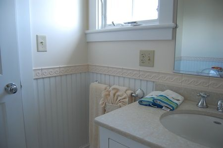 A bathroom with a sink , mirror and window.