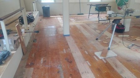 A person is cleaning a wooden floor with a mop.