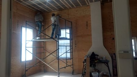 A man is standing on a scaffolding in a room.