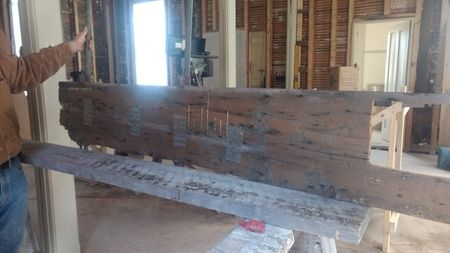 A man is holding a large piece of wood in a room.