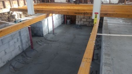 A basement under construction with wooden beams and a concrete floor.