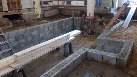 A brick wall is being built in a basement.
