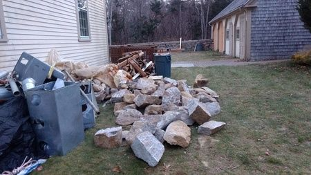 A pile of rocks is sitting in the grass in front of a house.