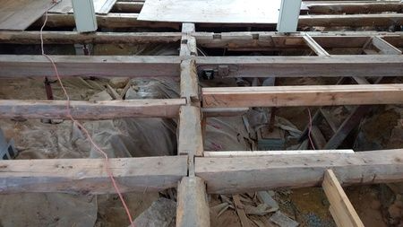 A wooden floor with a few pieces of wood missing.