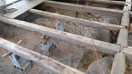 A wooden floor is being built in a hole in the ground.