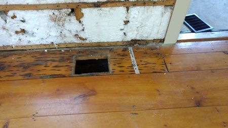 A wooden floor with a hole in the wall.