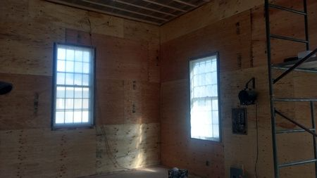 A room with two windows and a ladder in it.