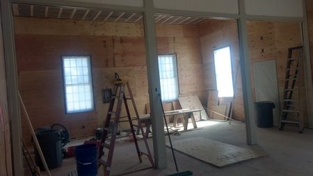 A room with a ladder and a broom in it is being remodeled.