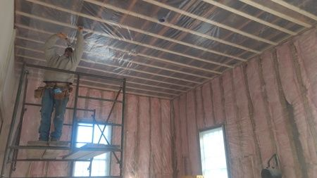 A man is standing on a scaffolding in a room.