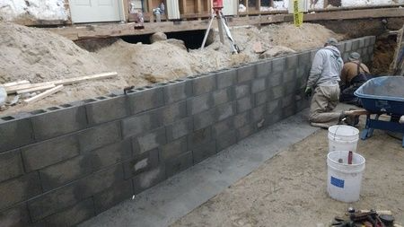 A group of men are working on a brick wall.