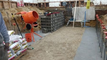 A construction site with a concrete mixer and a pile of bricks.