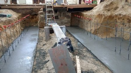A concrete walkway is being built in a basement.