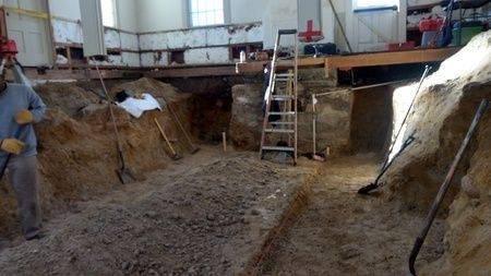 A man is digging a hole in the ground in a building.