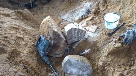 A person is digging a hole in the dirt with a hammer.