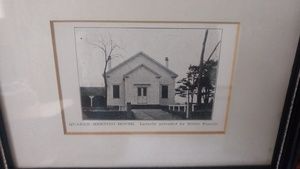 A black and white photo of a church in a frame.