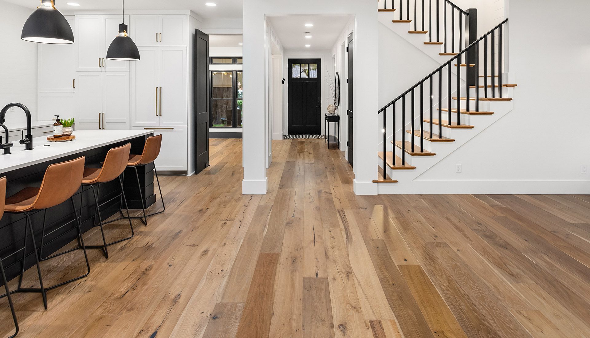 A kitchen with hardwood floors and stairs in a house.