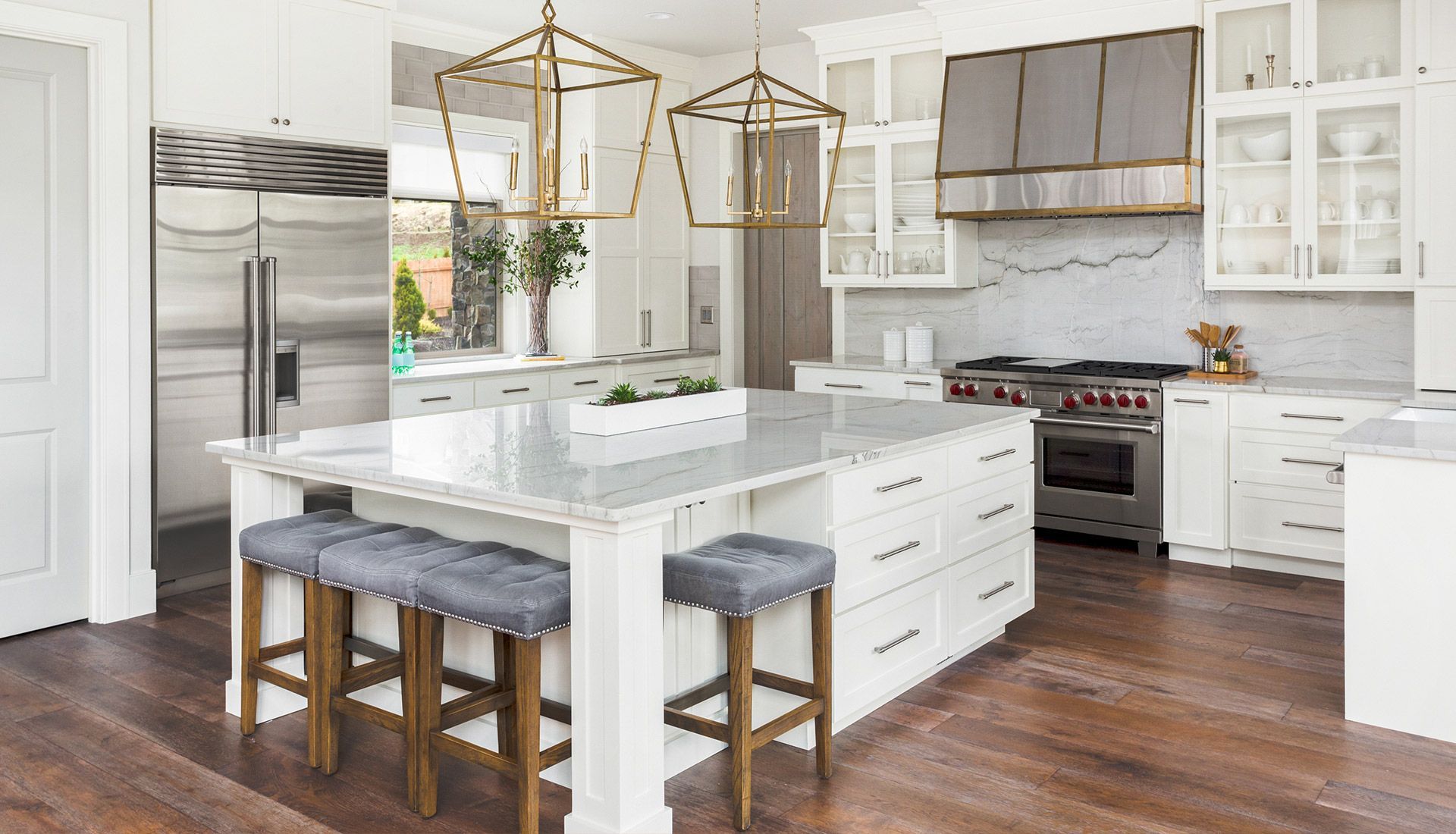 A kitchen with white cabinets and stools and a large island in the middle.