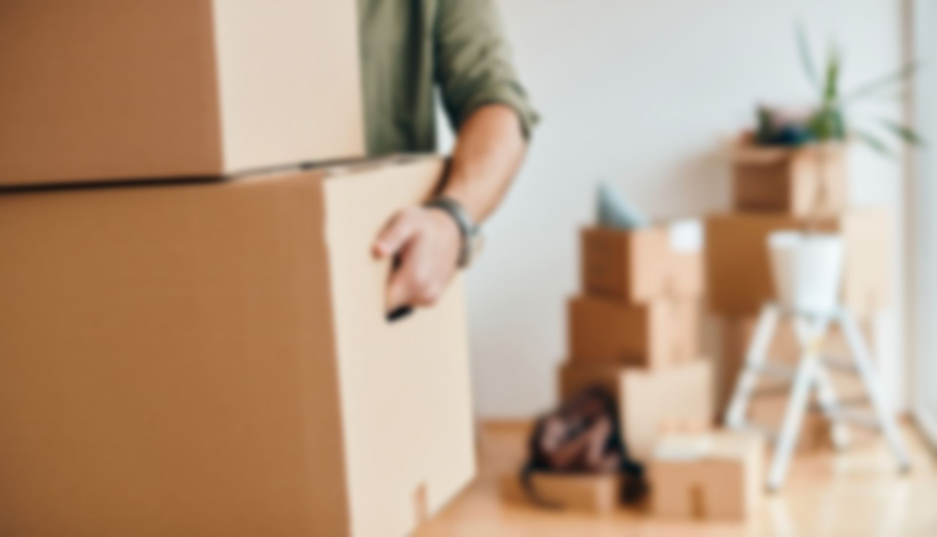 A man is carrying a cardboard box in a living room.