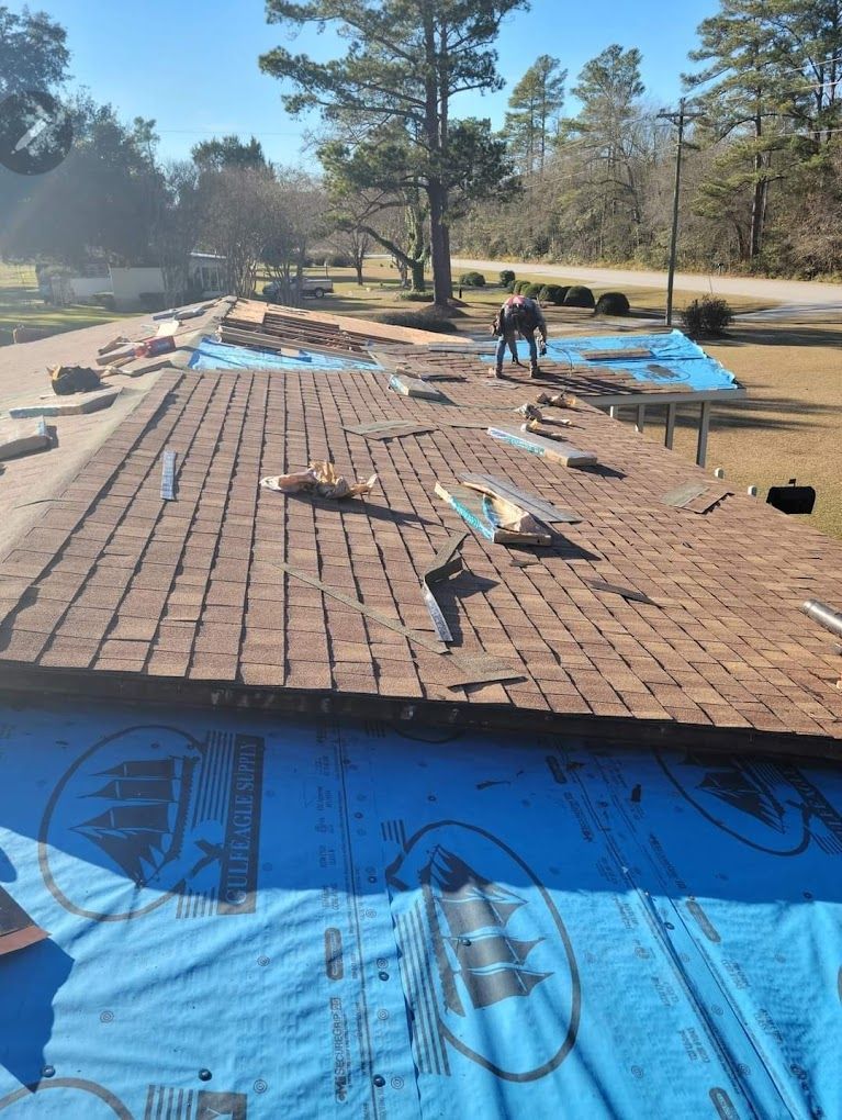 A man is working on a roof with a blue tarp on it.