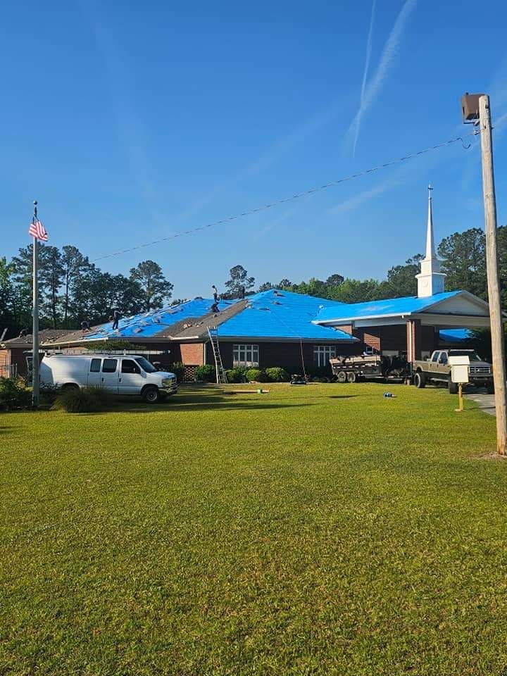 A church with a blue tarp on the roof is being remodeled.