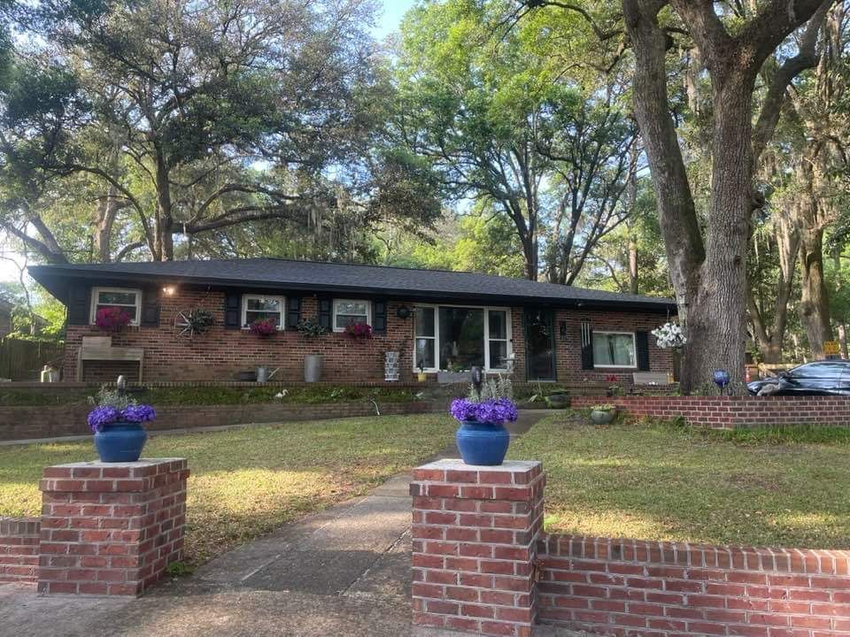 A brick house with purple flowers in front of it