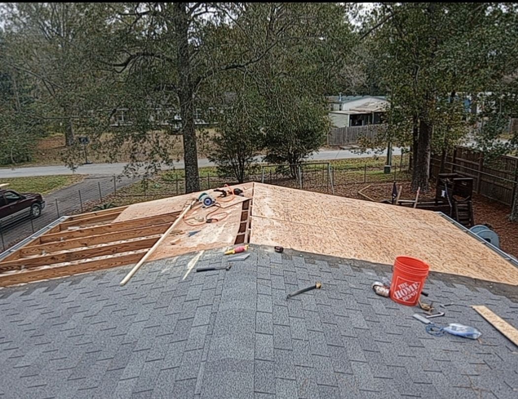 A roof is being built on a house with a red bucket on the roof.