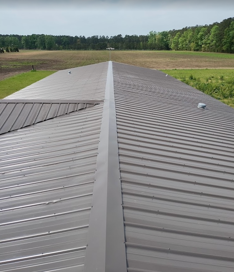 An aerial view of a metal roof with a field in the background.