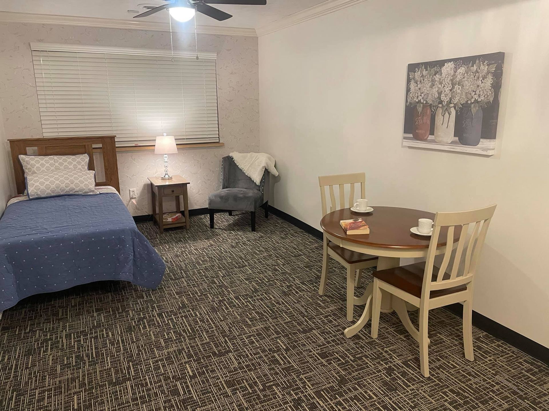 A bedroom with a single bed , table and chairs.