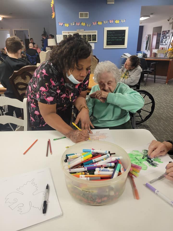 A nurse is helping an elderly woman with a drawing