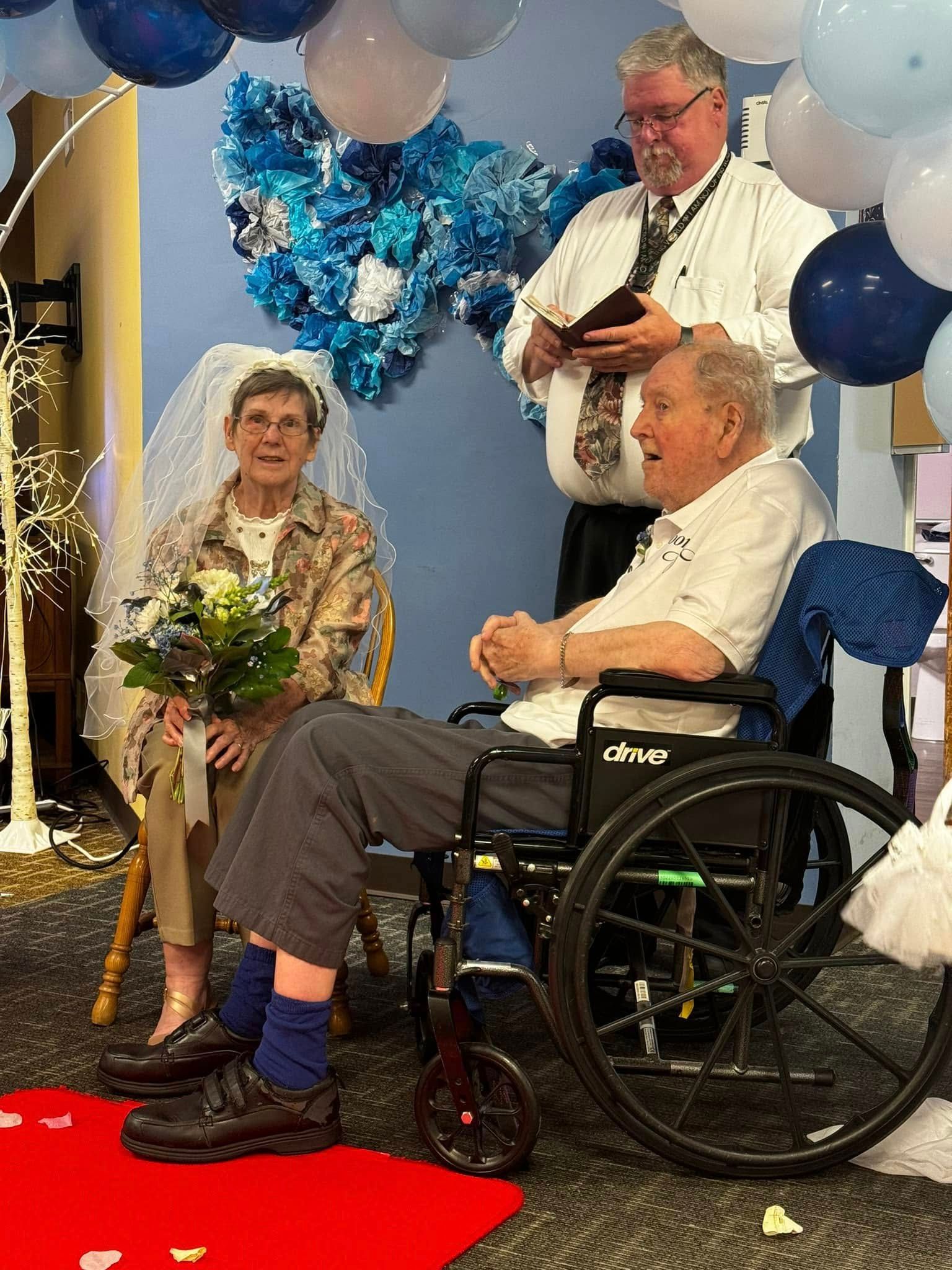 A man in a wheelchair is sitting next to a woman in a veil.
