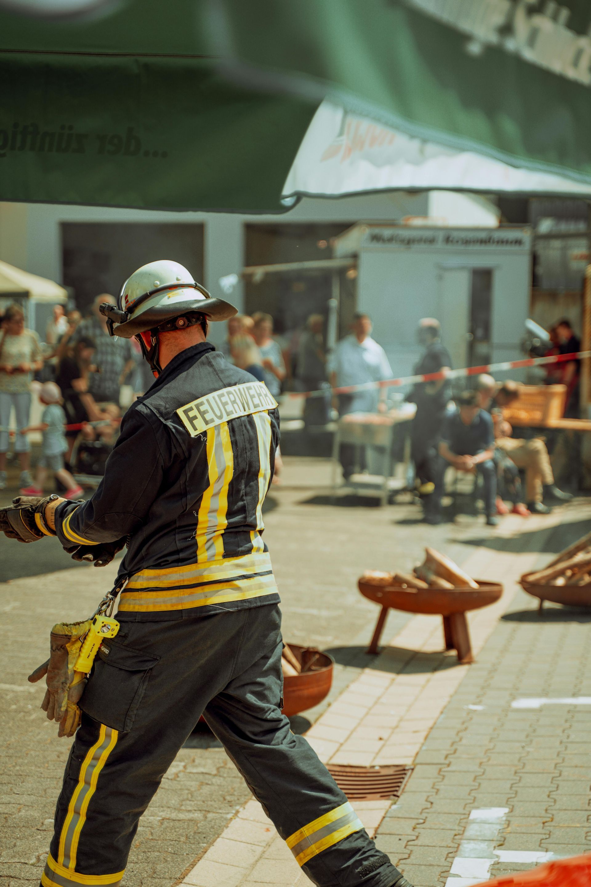 A fireman is walking down the street holding a fire extinguisher.