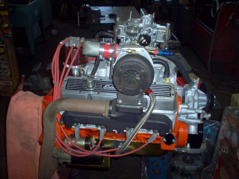 Orange engine block with silver components, a turbocharger, and orange and red wiring.