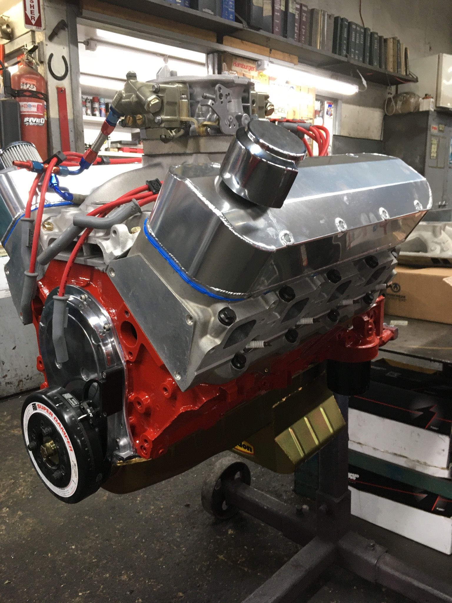 Red engine with polished aluminum components, in a workshop setting.