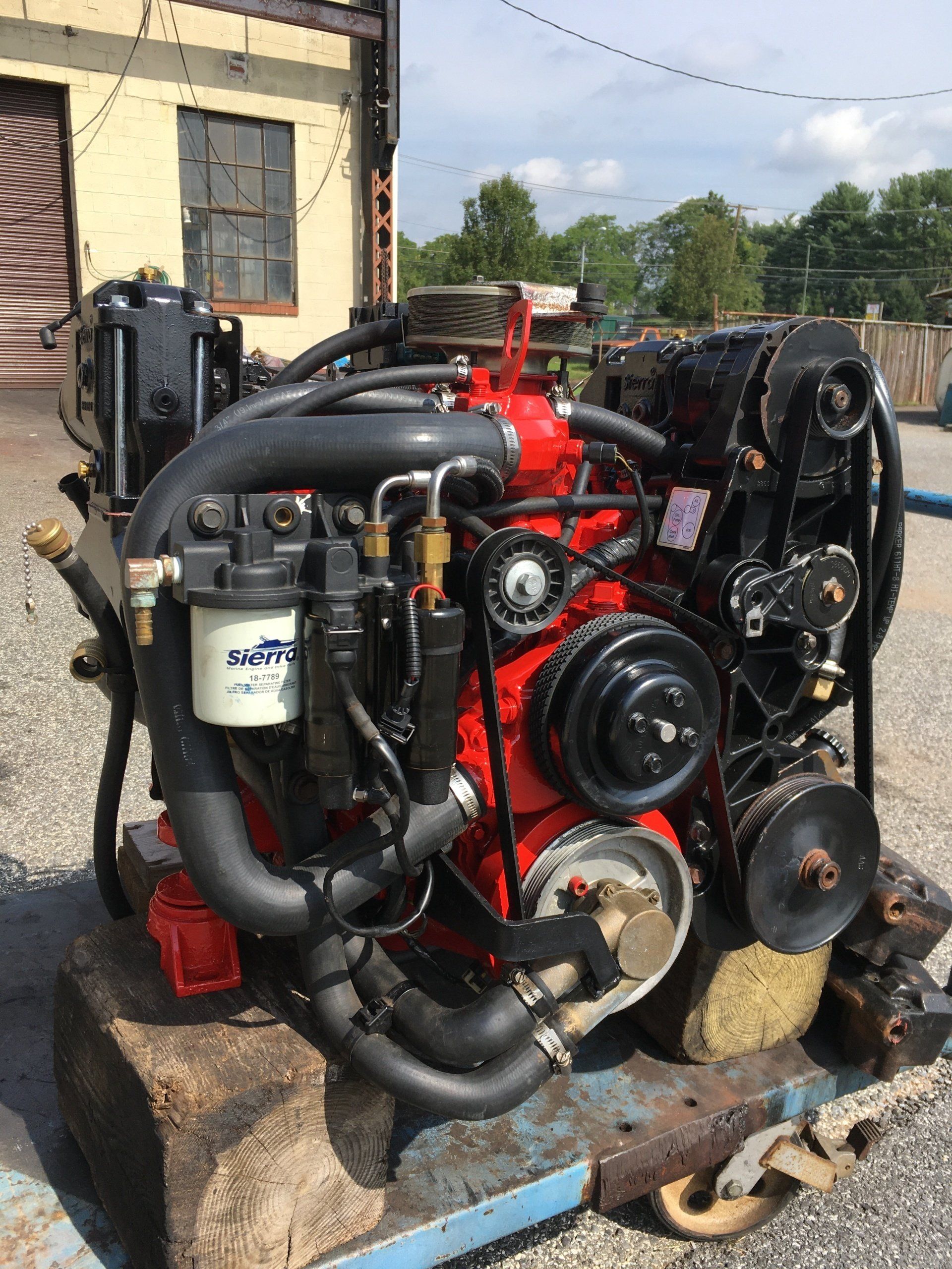 Red and black boat engine, various hoses and components visible, outdoors.