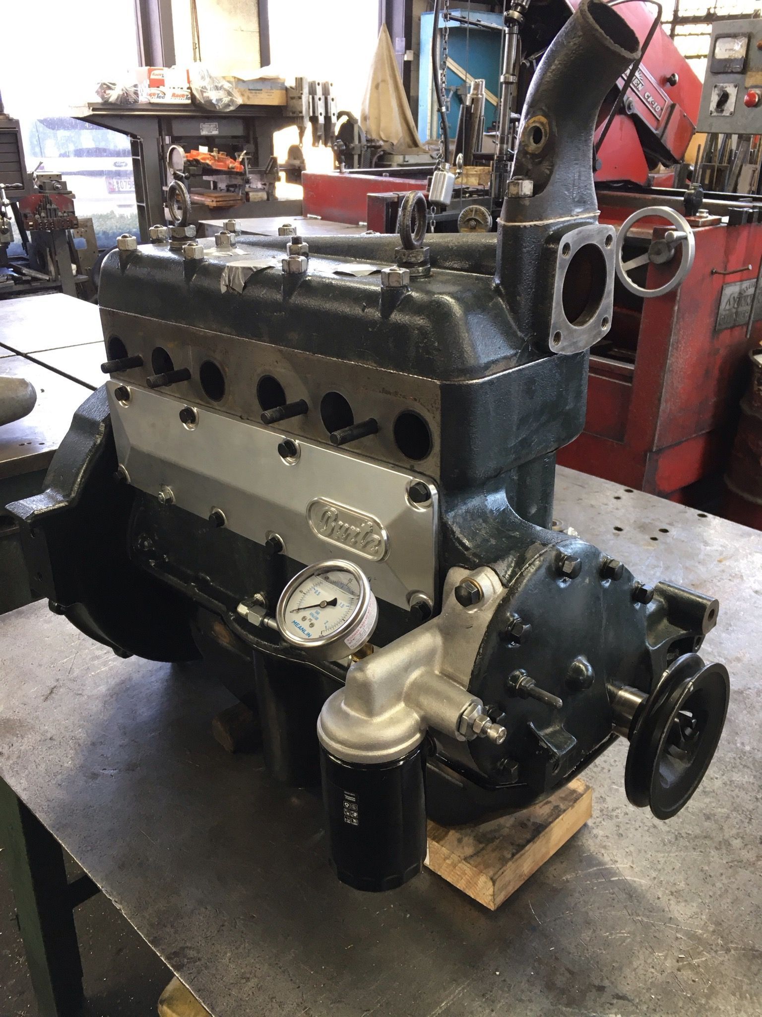 A black engine is sitting on a table with a gauge attached to it.