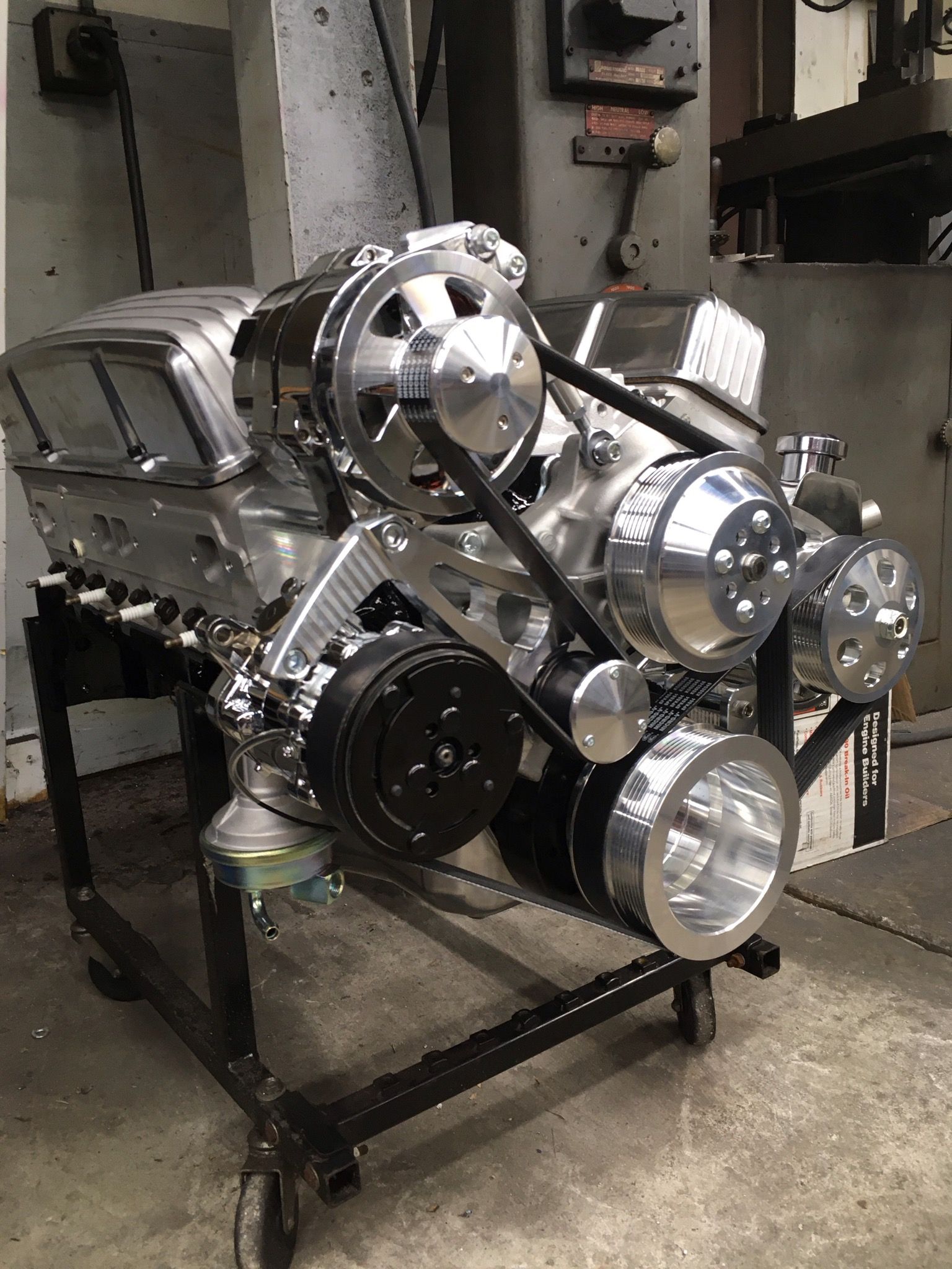 A chrome engine is sitting on a cart in a garage.